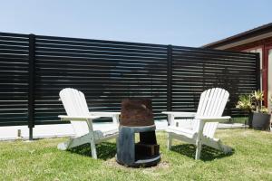 two chairs and a table with a grill in the grass at Sweet beautiful TINY HOME with pool and 2 minute drive to the beach in Wollongong