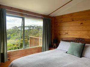 sypialnia z łóżkiem i dużym oknem w obiekcie Seaview, Sun and Surf - Piha Holiday Home w mieście Piha