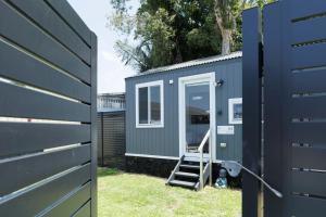 卧龙岗Sweet beautiful TINY HOME with pool and 2 minute drive to the beach的 ⁇ 旁的蓝色小房子