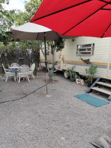 - un parasol rouge, une table et des chaises ainsi qu'une caravane dans l'établissement Casa rodante los cachorones, à Loreto
