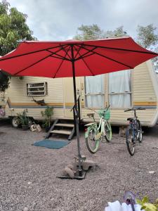 um guarda-chuva vermelho na frente de um reboque com uma bicicleta em Casa rodante los cachorones em Loreto