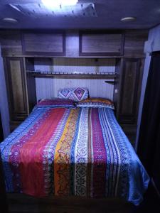 a bed with a colorful blanket on top of it at Casa rodante los cachorones in Loreto
