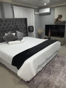 een slaapkamer met een groot wit bed en een zwarte deken bij 54 Malcolm Palace Room in Durban