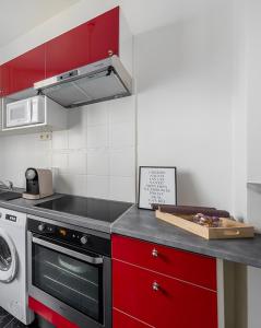 La cuisine est équipée de placards rouges et d'un four avec plaques de cuisson. dans l'établissement Nouveau T2 à 7 min de Saint-Lazare, à Asnières-sur-Seine