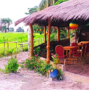 eine Hütte mit einem Tisch und Stühlen auf einem Feld in der Unterkunft Campement Kaymba Lodge in Kachiouane