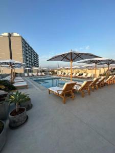 un gruppo di sedie e ombrelloni accanto alla piscina di Apartamento de estreno San Bartolo vista Piscina Playa a San Bartolo