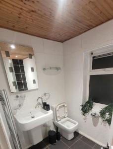 a white bathroom with a sink and a toilet at Three Bed House with free on-site parking Sleeps 5 in Warrington