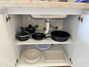 a kitchen shelf with two pots and pans under a sink at 2 Min da Praia! / 2 Quartos / Vaga de Garagem in Santos +4 photos