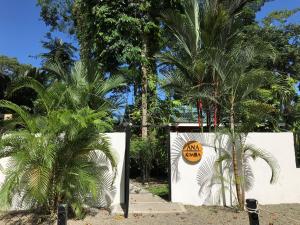 a white wall with a sign on it next to palm trees at Casa ANA KIMBA in Puerto Viejo