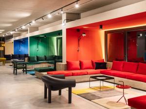 uma sala de estar com um sofá vermelho e cadeiras em Ibis Styles Roma Aurelia em Roma