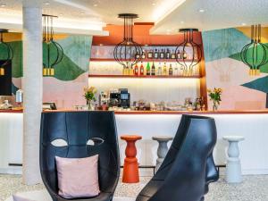 a chair with a pillow in front of a bar at ibis Styles St Margrethen Bodensee in Sankt Margrethen