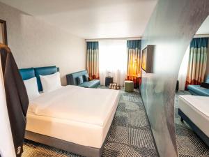 ein Hotelzimmer mit einem Bett und einem Sofa in der Unterkunft ibis Styles St Margrethen Bodensee in St. Margrethen