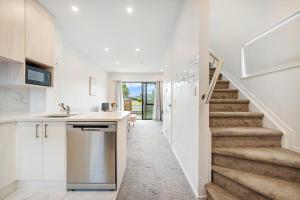 eine Küche und eine Treppe in einem Haus mit weißen Wänden in der Unterkunft Cozy Brand New Townhouse 3 in Auckland
