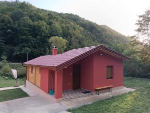 a small red building with a hill in the background at Milica 2 in Crni Vrh