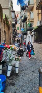 Une femme marchant dans une rue avec des fleurs dans des seaux dans l'établissement Panariello a Portamedina, à Naples