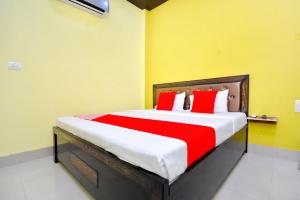 OYO Blue Sky Guest House في Kurukshetra: غرفة نوم بسرير كبير ومخدات حمراء وبيضاء