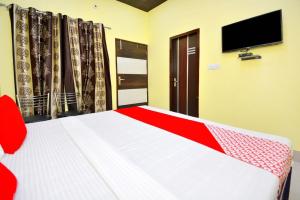 OYO Blue Sky Guest House في Kurukshetra: غرفة نوم مع سرير وتلفزيون على الحائط