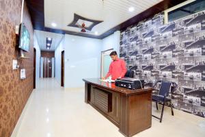 OYO Blue Sky Guest House في Kurukshetra: رجل يقف عند مكتب