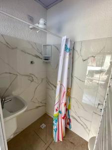 y baño con cortina de ducha y lavamanos. en Casa aconchegante em Peruíbe en Peruíbe