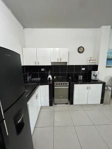 Una cocina con gabinetes blancos y un reloj en la pared. en ARMANI, en Puerto Colombia