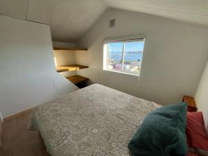 ein kleines Schlafzimmer mit einem Bett und einem Fenster in der Unterkunft Casa Miramar in Quellón