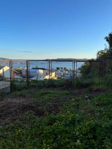 een hek in een veld met de oceaan op de achtergrond bij Casa Miramar in Quellón