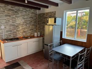 eine Küche mit einem Kühlschrank, einem Tisch und einem Fenster in der Unterkunft Casa Miramar in Quellón