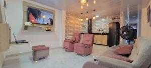 sala de estar con sofá, 2 sillas y TV en Apartahotel Los Ángeles en Cartagena de Indias