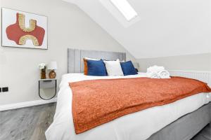 a bedroom with a large bed with orange blanket at City Getaway- Newly Renovated Flat for Groups in Greenford