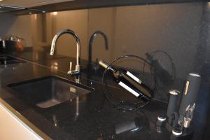 a black kitchen counter with a sink with a wine glass at JM Alojamento local no Porto in Porto +160 photos