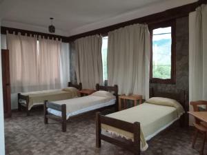 1 dormitorio con 3 camas, ventanas y mesa en Altos de la Pacha en Cafayate