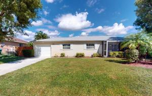 ein großes weißes Haus mit einem Rasenhof in der Unterkunft Hidden Gem: Escape to Newlin Cottage in Cape Coral in Cape Coral