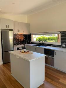 una cocina con armarios blancos y electrodomésticos de acero inoxidable en Corowa Bindaree Holiday Park, en Corowa