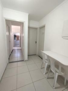 a white dining room with a table and chairs at Residência RCA13 in Santos