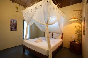 een slaapkamer met een hemelbed en witte gordijnen bij Fullmoon Bungalows in Toyapakeh