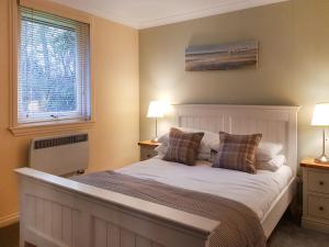 a bedroom with a bed with two lamps and a window at Leven Lodge 2 - Uk46044 in Balloch