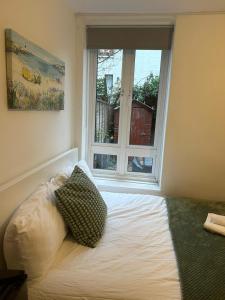 Bett mit zwei Kissen vor einem Fenster in der Unterkunft Lovely Double Rooms in Euston & Square in London