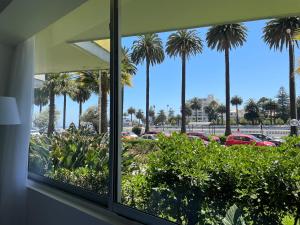 een raam met uitzicht op een parkeerplaats met palmbomen bij Lechón Marina in Viña del Mar +1 foto