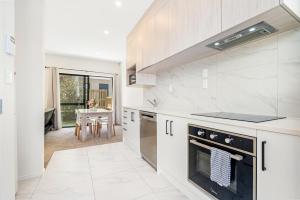 a kitchen with white cabinets and a stove top oven at Cozy Brand New Townhouse 20 in Auckland