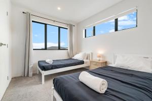 a bedroom with two beds and two windows at Cozy Brand New Townhouse 20 in Auckland