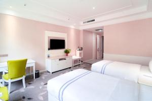Huayin的住宿－华山欣源国际酒店，一间卧室配有两张床、一张桌子和一台电视。