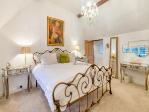 una camera con un letto e due tavoli e un lampadario a braccio di The Cottage a Hungerton