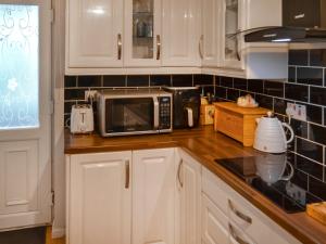 una cocina con armarios blancos y microondas en una encimera en Swallow Lodge, en Horsington