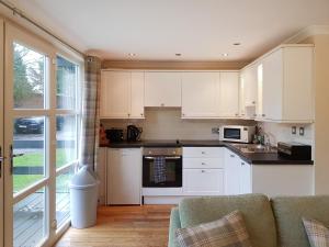 a kitchen with white cabinets and a couch at Leven Lodge 3 - Uk46045 in Balloch