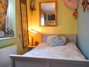 una camera da letto con un letto con uno specchio sul muro di Dormys Cottage a Skegness