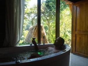 Un uomo nella vasca da bagno con un bicchiere di vino di Ecohabs Bamboo Parque Tayrona - Dentro del PNN Tayrona a El Zaino