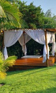 uma cama de dossel com cortinas brancas na relva em Costa do Sauipe Casa dentro do complexo hoteleiro na Costa do Sauípe