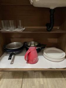 a table with plates and pans and a red tea kettle at Apartamento próximo ao centro in Primavera do Leste