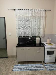 a kitchen with a stove and a window at Apartamento próximo ao centro in Primavera do Leste