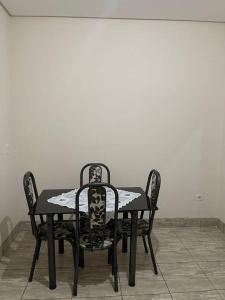 a black table with two chairs and a table and a wall at Apartamento próximo ao centro in Primavera do Leste